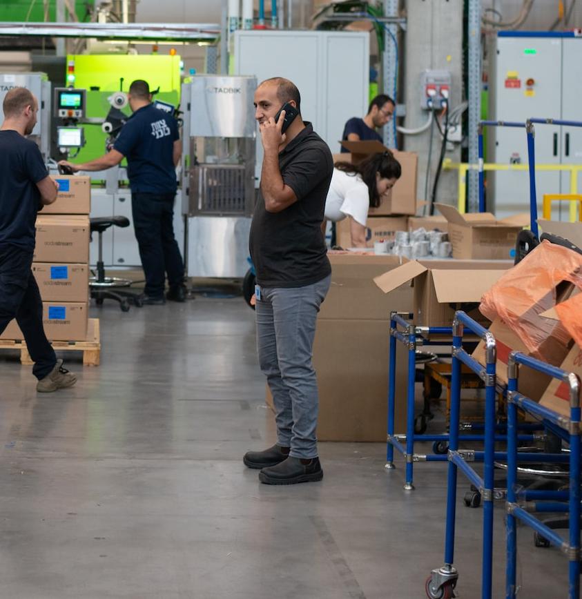 man in gray shirt standing beside brown cardboard boxes